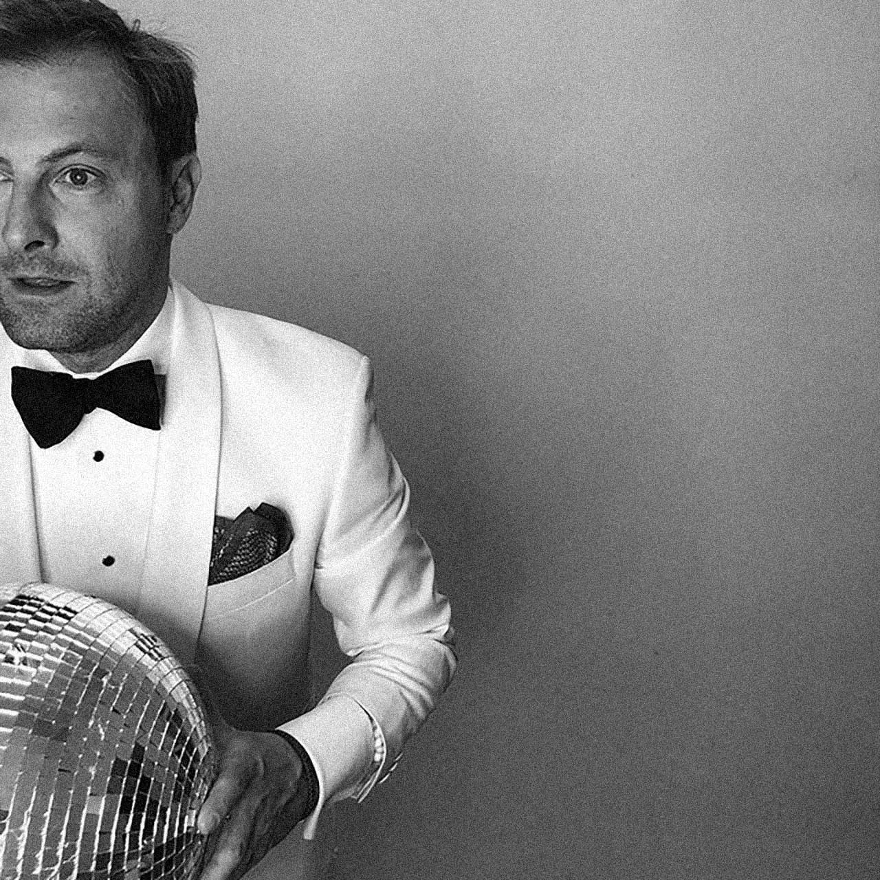 DJ Dandy O. in a white tux, holding a disco ball.